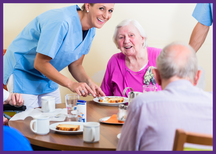 photo of a smiling nursing home employee serving residents food in a dining room - when you need to choose a nursing home, consider the food