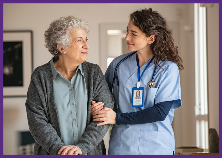 photo of an aide walking with a senior woman in a nursing home, holding her by the elbow - when you need to choose a nursing home, consider the staffing ratios
