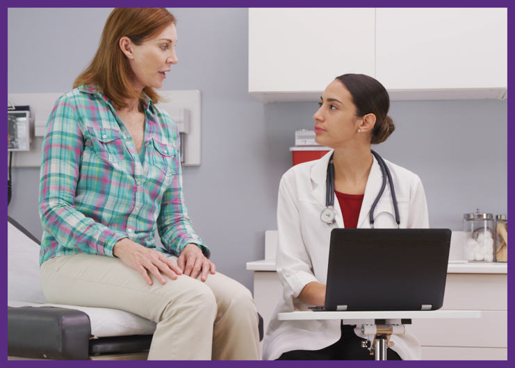photo of a doctor sitting on a stool with a laptop, while speaking with a female patient who is on an exam table - you should switch doctors if your doctor doesn't look up from their computer
