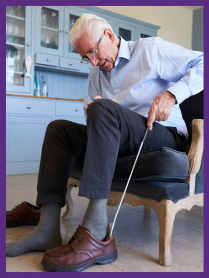 photo of a senior man using a long shoe horn to put his shoes on 