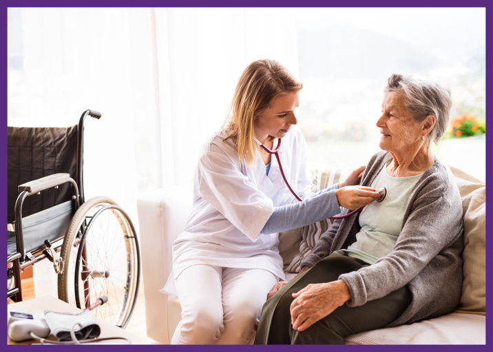 photo of a nurse listening to the heart of a senior woman in her home as they both sit on the sofa