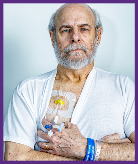 photo of a senior male pulling his t-shirt down to expose the medication port in his chest 