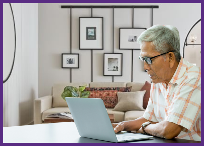 photo of a senior man sitting at a table at home, using his laptop computer - researching possible infusion providers can help you reduce your chance of home infusion therapy risks 